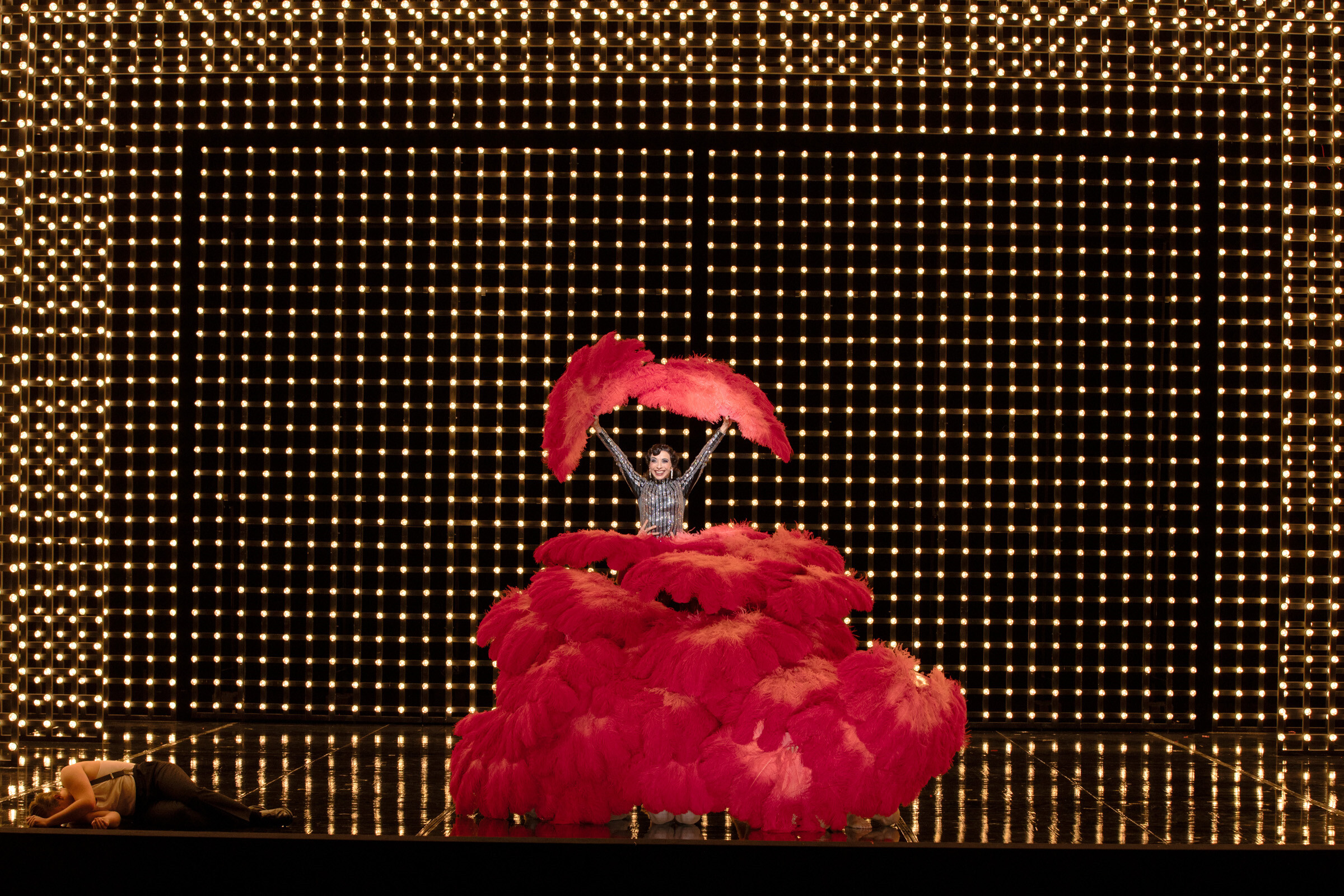 Ruth Brauer-Kvam als Velma Kelly umhüllt von roten Federflügeln auf der Bühne der Komischen Oper Berlin im Schillertheater