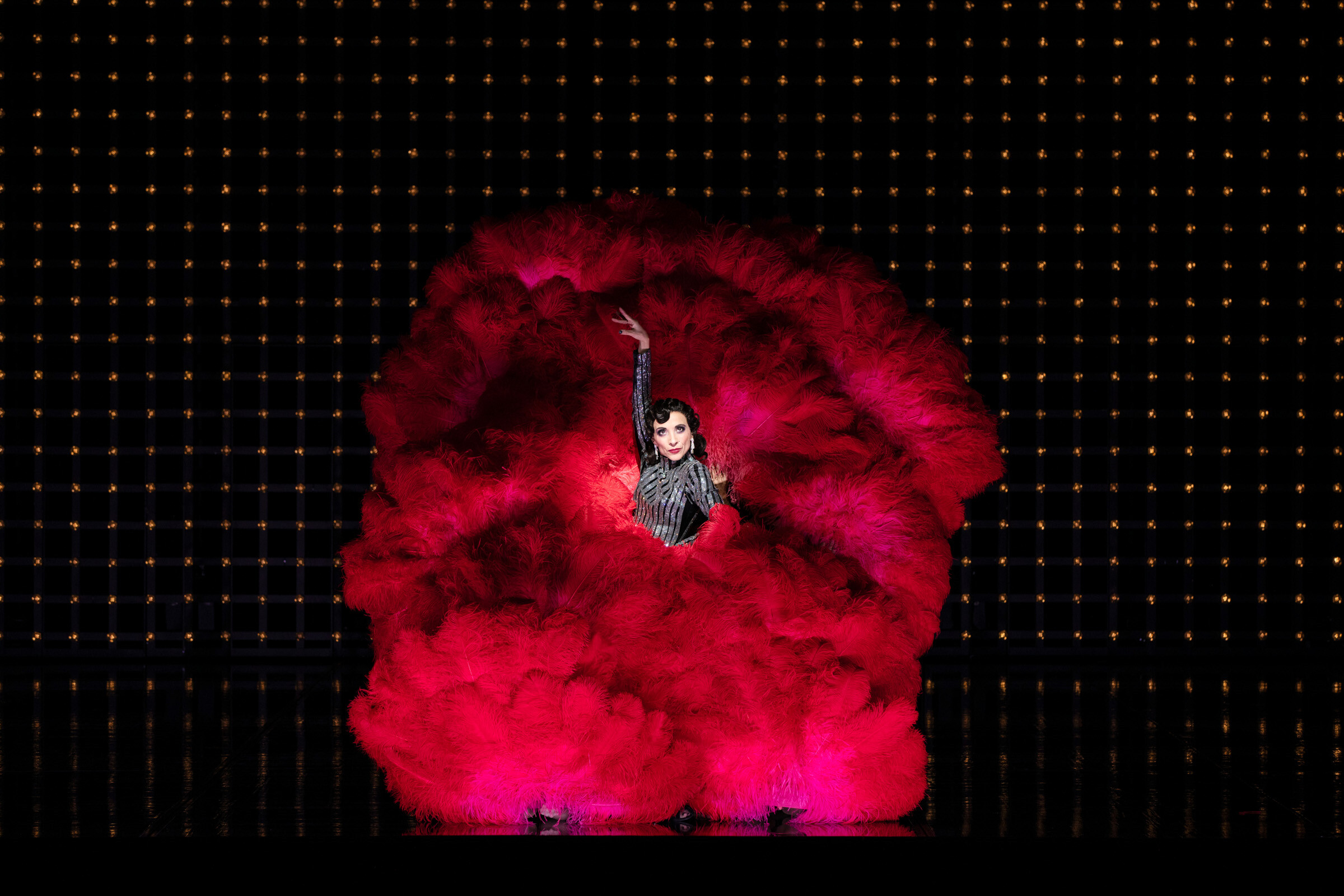 Ruth Brauer-Kvam als Velma Kelly umhüllt von roten Federflügeln auf der Bühne der Komischen Oper Berlin im Schillertheater
