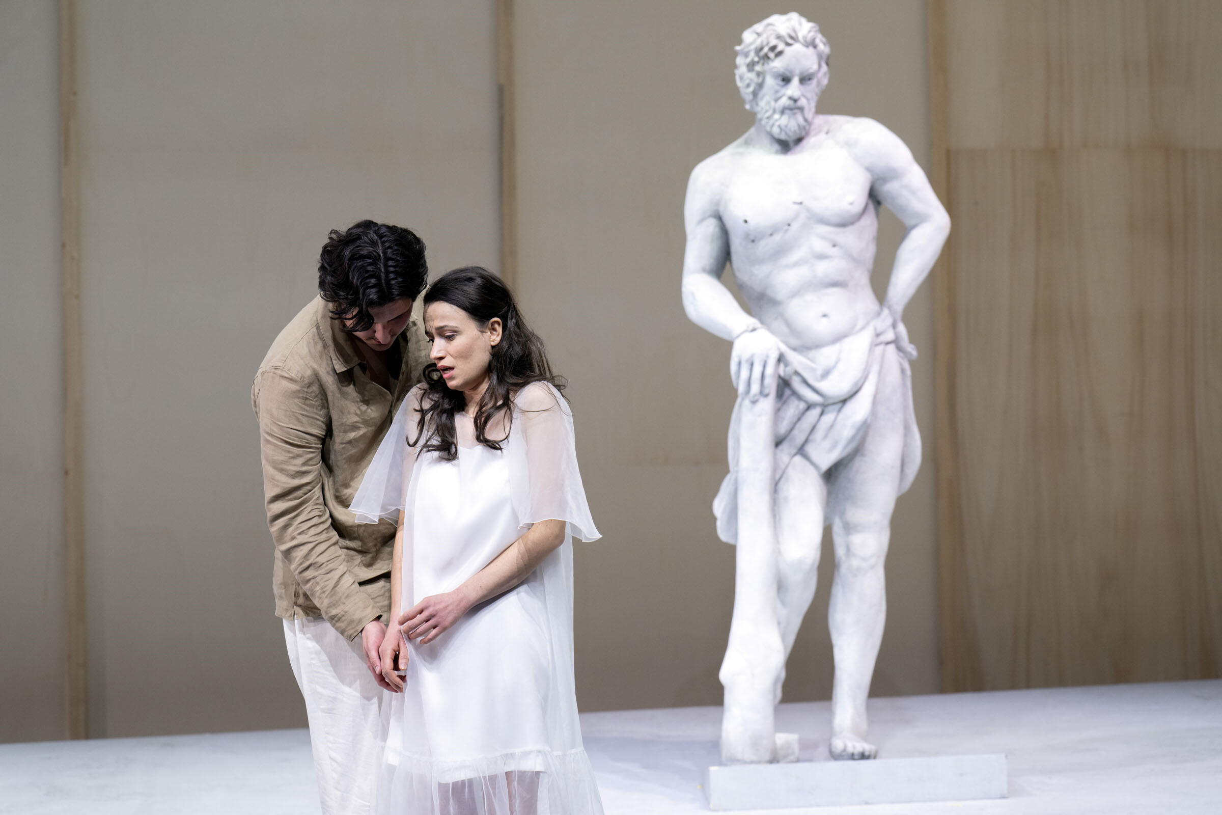 Caspar Singh als Hyllus umarmt Penny Sofroniadou als Iole von hinten, rechts Statue des Hercules